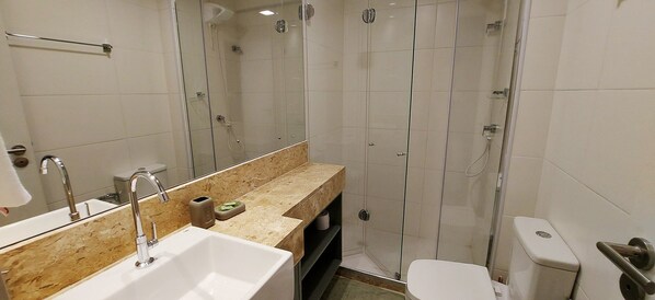 Une salle de bain moderne avec une douche à parois de verre, un lavabo doté d’un plan de toilette en marbre et des toilettes.
