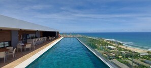 A poolside area with a view of the ocean, outdoor seating, and a bar area. - COSTE0104 - Premium Stella Maris (Salvador)
