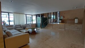 Un vaste espace de vie comprenant un ensemble de canapés, une table basse et un escalier menant à l’étage supérieur.