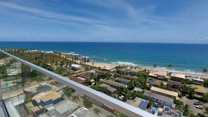 Un quartier résidentiel en bord de mer, avec une plage, des maisons dotées de panneaux solaires et une vue dégagée sur l’océan.