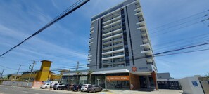 A modern building with a prominent sign for 'PREMIUM ESTELLA MARIS' and a parking lot with several cars.