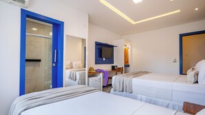 Habitación de hotel con dos camas, un escritorio, un espejo y zona de ducha.