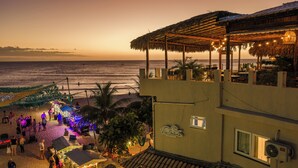 A beachfront property with a covered outdoor seating area, a beachside bar, and a view of the ocean.