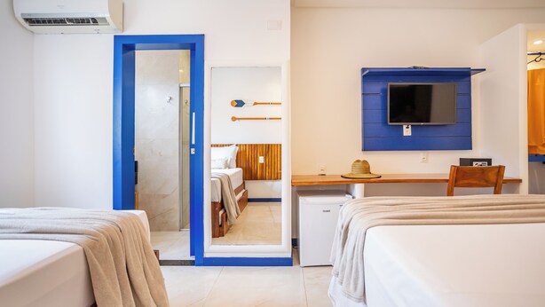 A hotel room with two beds, a desk, a television, and a small refrigerator.