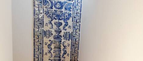 Una escalera con baldosas azules y blancas de diseño en las paredes y escalones de madera.
