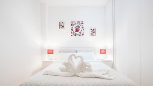 A hotel room with a neatly made bed, two bedside lamps, and three wall art pieces.