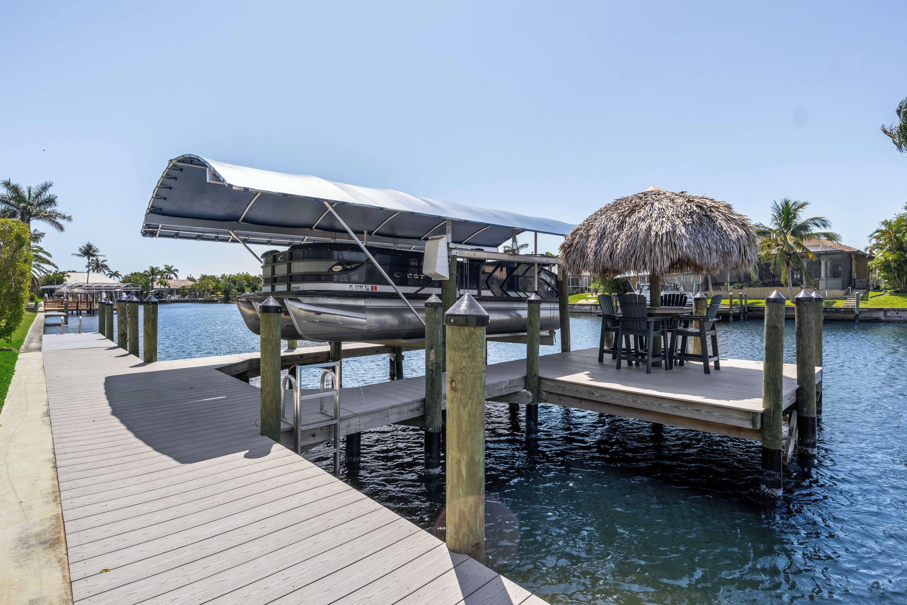 A dock with a boat, a thatched umbrella, and a water view.
