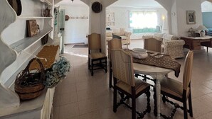 A spacious living area with a dining table, chairs, and a sofa. There are shelves with decorative items and a chandelier. - DOMO MEA beautiful farmhouse immersed in theSardinian countryside an its animals (Nulvi)