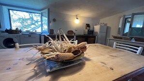 A kitchen with a wooden table, a microwave, and a washing machine. - DOMO MEA beautiful farmhouse immersed in theSardinian countryside an its animals (Nulvi)