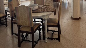 A spacious living area with a high ceiling, a dining table with chairs, and a sofa. - DOMO MEA beautiful farmhouse immersed in theSardinian countryside an its animals (Nulvi)
