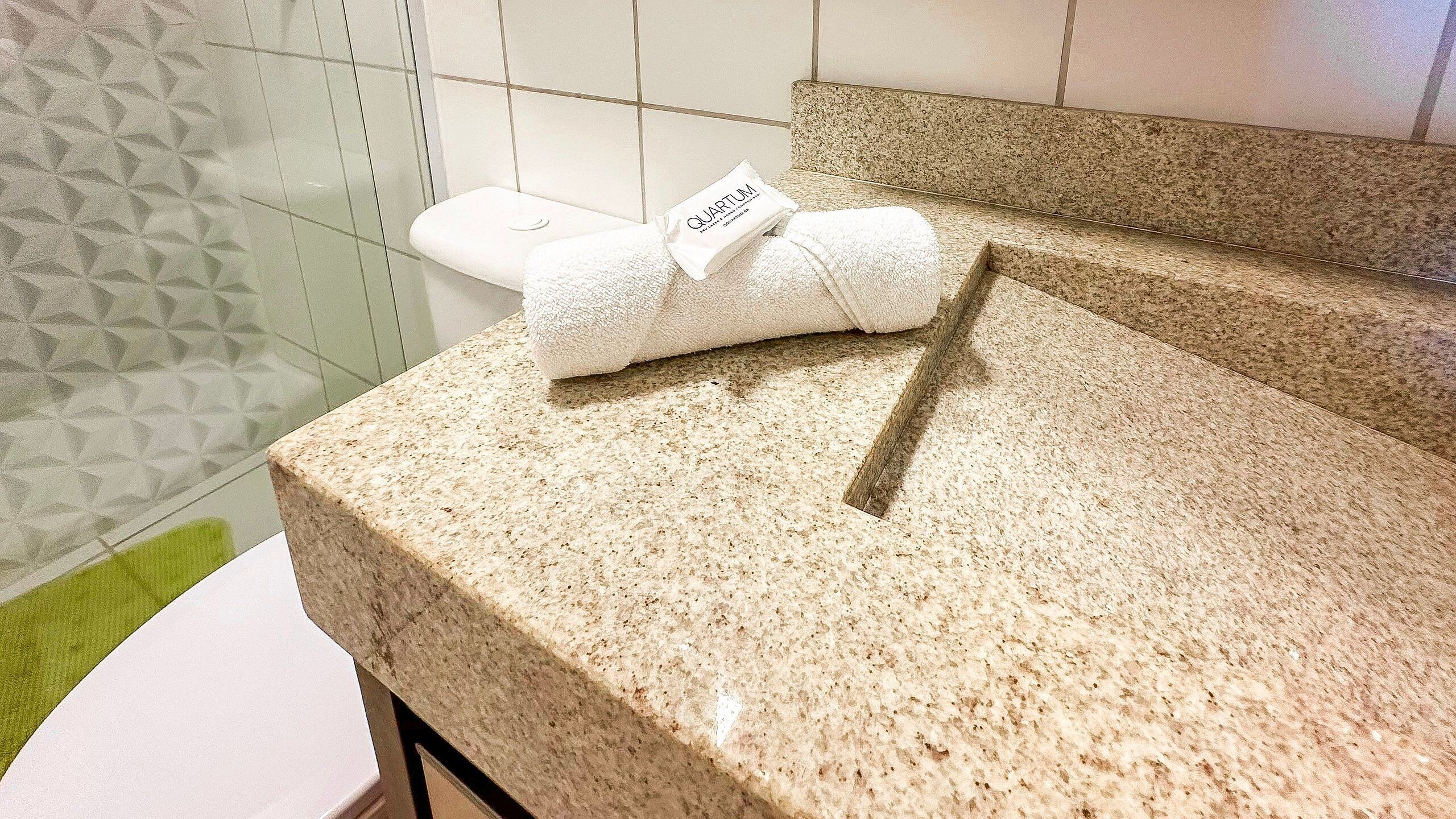 A bathroom with a granite countertop, a white toilet, and a towel placed on the counter.