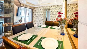 A dining area with a table set for four, chairs, a vase with flowers, and a glass cabinet with wine glasses. - Resid. Clube Mar Grosso-Laguna - LAG905 (Laguna)
