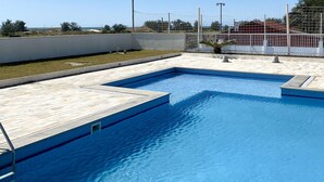 A rectangular swimming pool with a tiled deck, surrounded by a white fence and a clear blue sky. - Resid. Clube Mar Grosso-Laguna - LAG905 (Laguna)
