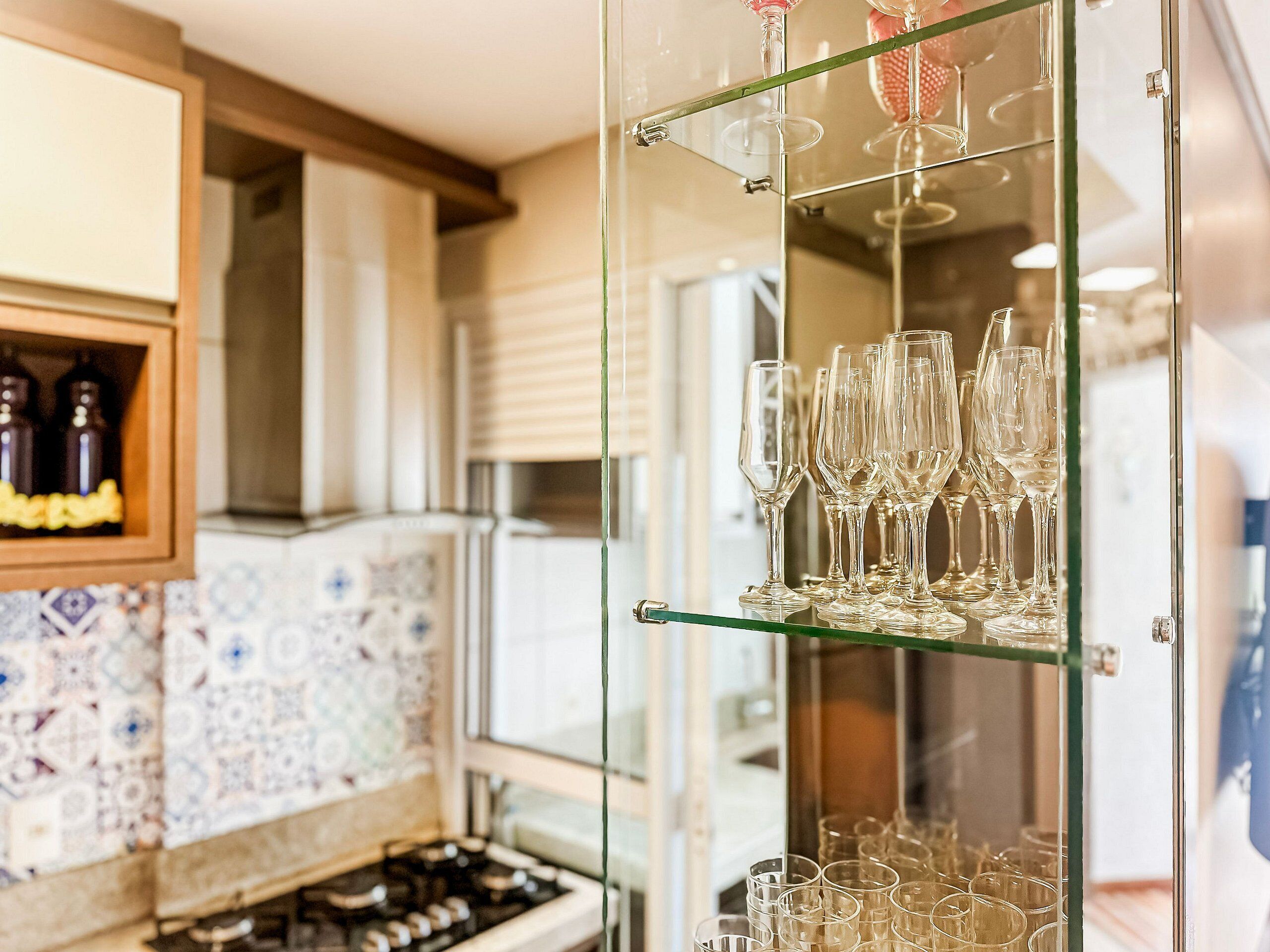 Una cocina con una vitrina de vidrio que contiene copas y botellas de vino.