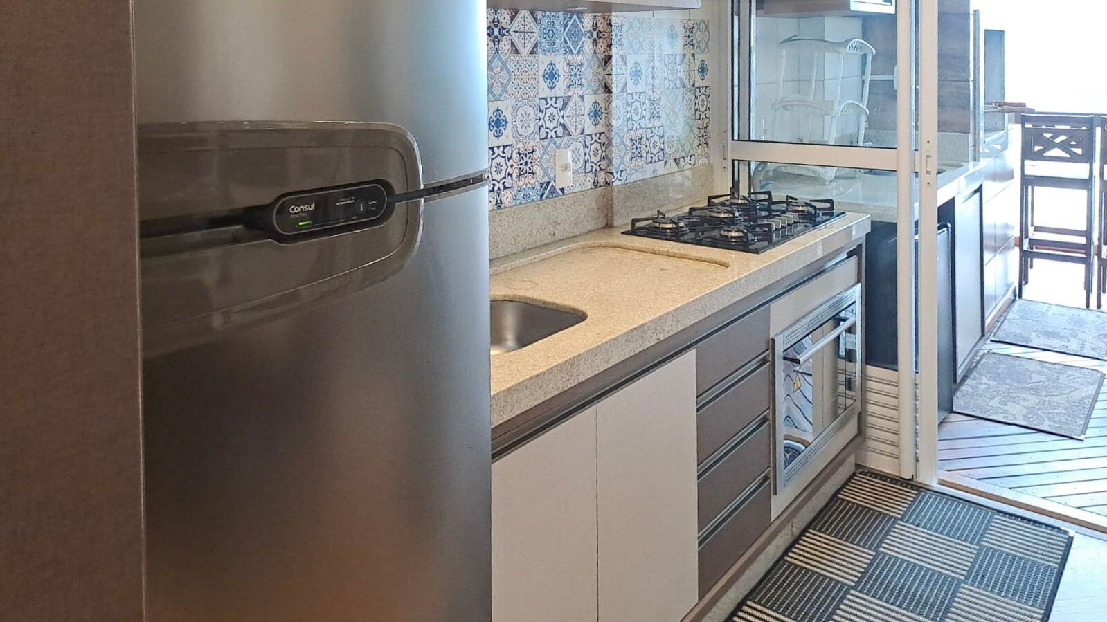 Een keuken met een roestvrijstalen koelkast, een gasfornuis en een spoelbak.