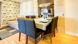 Comedor con una mesa dispuesta para cuatro personas, rodeada de sillas tapizadas en azul con patas de madera.