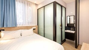 A hotel room with a bed, a wardrobe, a mirror, and a sink. - Liru Tujia Hostel (Beijing)