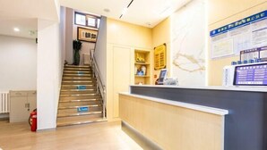 A reception area with a staircase, a reception desk, and a wall with informational posters. - Liru Tujia Hostel (Beijing)