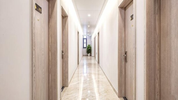 A hotel corridor with wooden doors, a marble floor, and a plant in the distance. - Liru Tujia Hostel (Beijing)