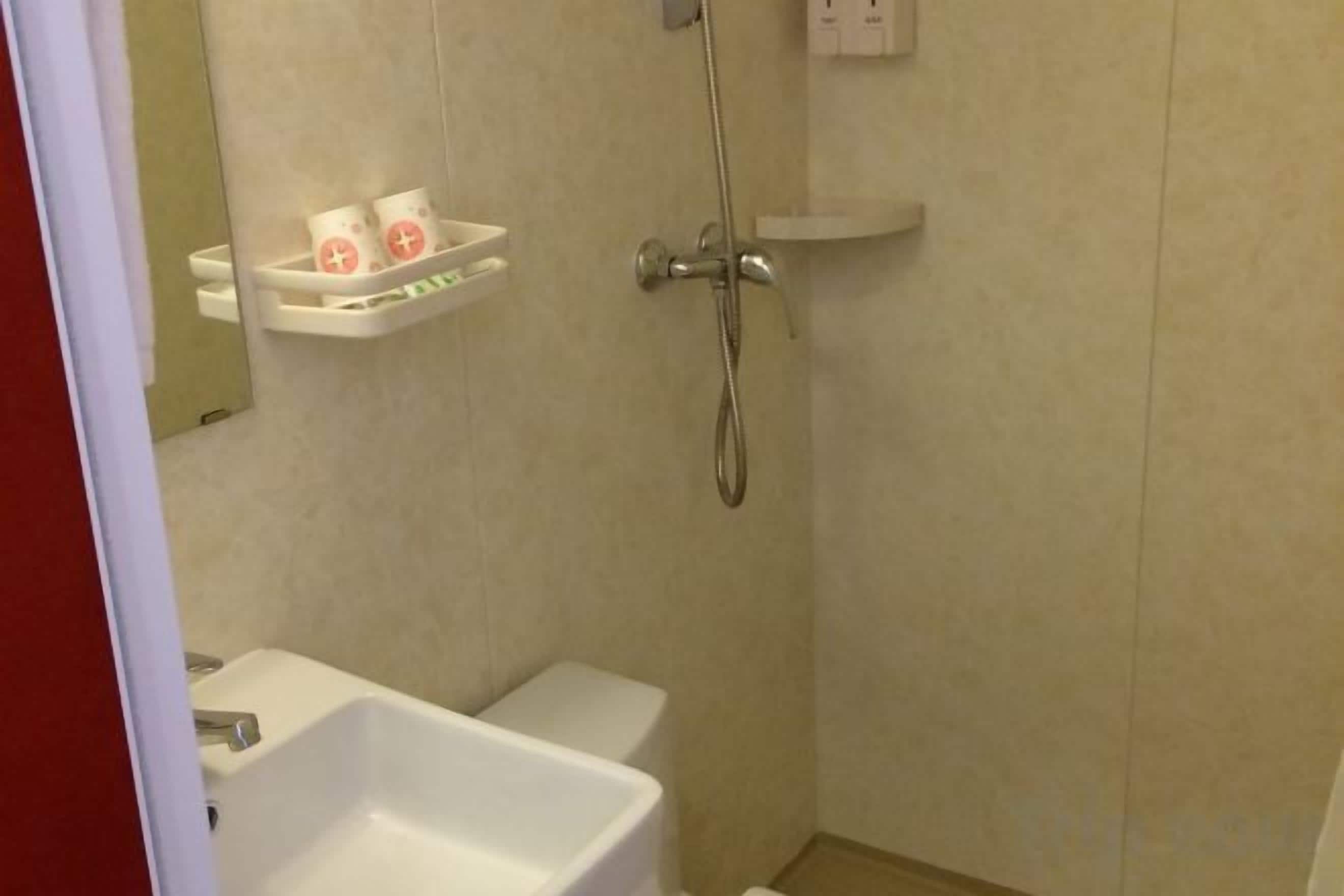 A bathroom with a sink, a shower, and a shelf with toiletries.