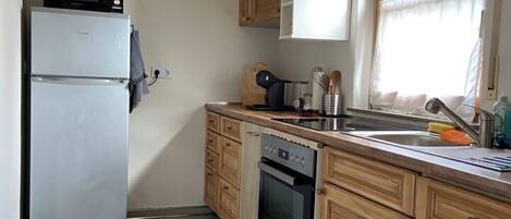 A compact kitchen with a refrigerator, microwave, oven, and sink.