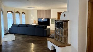 Ein Wohnzimmer mit einem dunkelgrauen Sofa, einem Fernseher und einem dekorativen Kamin.