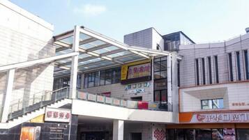 A multi-level commercial building with a glass facade, a staircase, and various storefronts.
