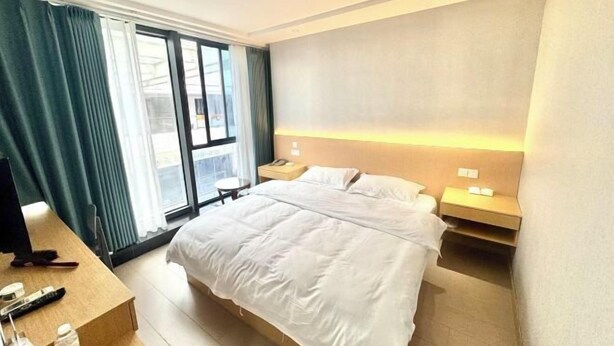 A hotel room with a large bed, a desk with a computer, a chair, and a window with curtains. - Yixing Hotel (Shanghai Zhujiajiao Ancient Town Scenic Area Branch) (Shanghai)