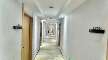 A long, narrow hotel corridor with doors on both sides, each marked with a number.