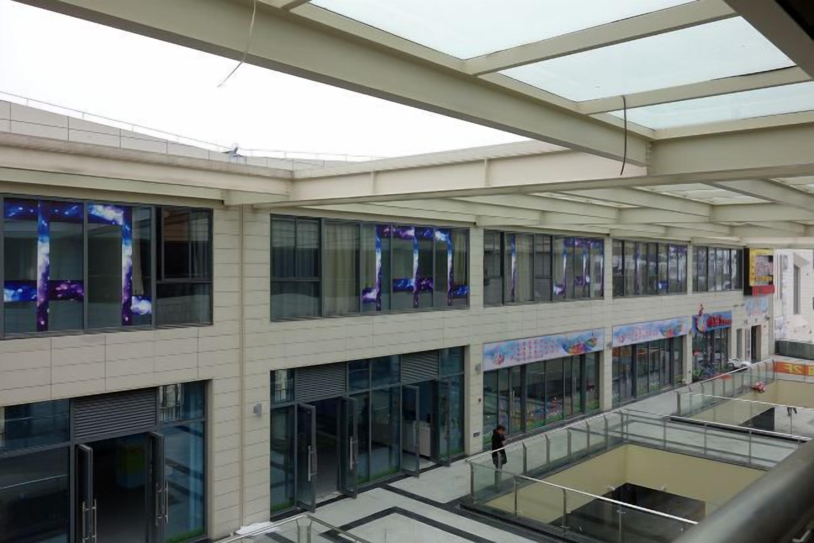 A multi-level building with glass railings, large windows, and a flat roof structure.