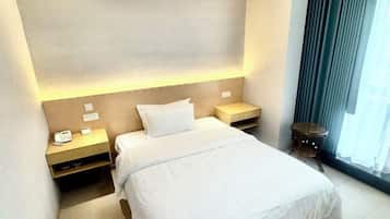 A hotel room with a bed, bedside tables, a phone, and a window with curtains.