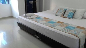 A hotel room with a bed, a window, and a bathroom visible in the background.