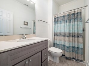 A bathroom with a white sink, a toilet, and a shower curtain with a blue and white pattern. - Green Dolphin by Topsail Realty (Holly Ridge)