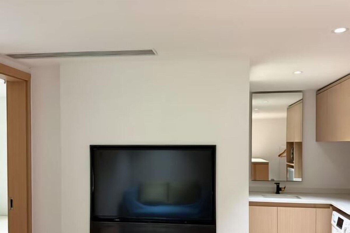 Una cocina moderna con televisión de pantalla plana, armarios de madera y encimera.