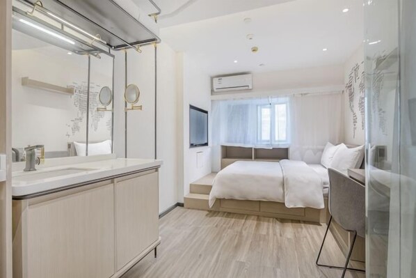 A modern bedroom with a large bed, a vanity with a mirror, and an air conditioning unit.