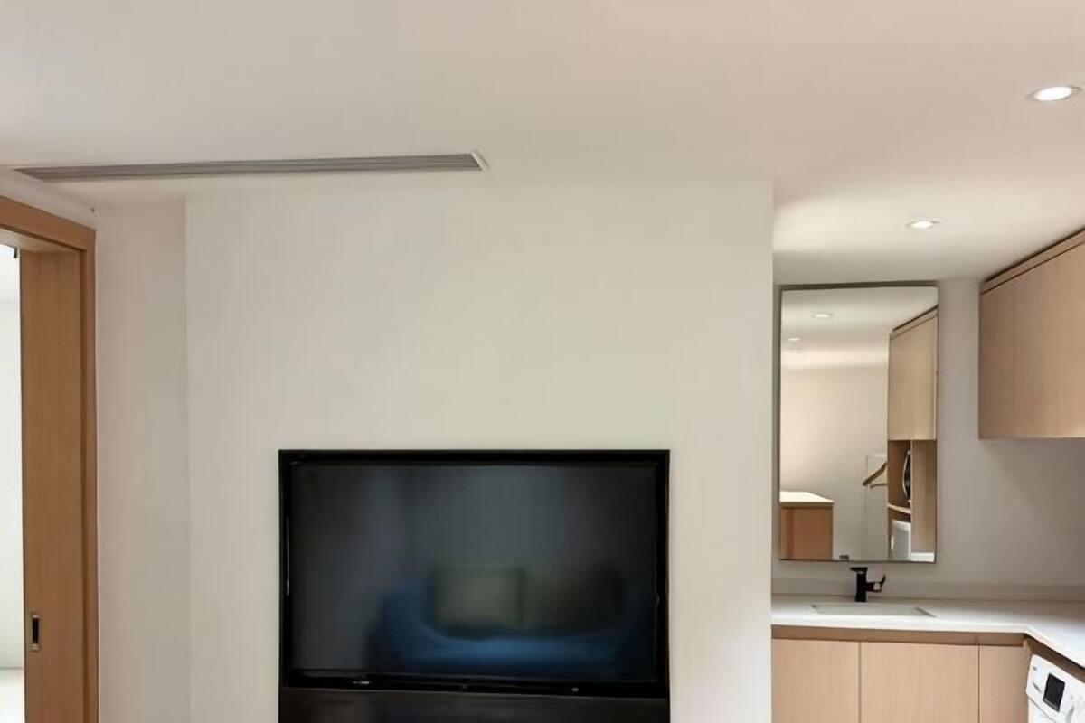 A modern kitchen with a flat-screen TV, wooden cabinets, and a countertop.