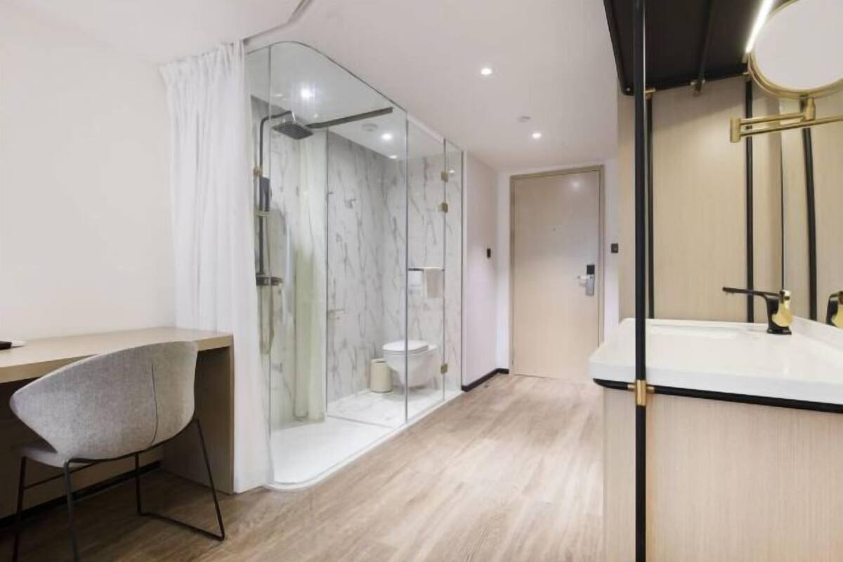 A modern bathroom with a glass shower enclosure, a white sink, and a wooden vanity.