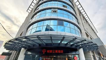 A modern building with a curved glass facade and a sign indicating a hotel.
