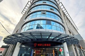 A modern building with a curved glass facade and a sign indicating a hotel. - CJIA Apartment Hotel (Shanghai Qibao) (Shanghai)