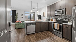 A modern kitchen with dark wood cabinets, stainless steel appliances, and a central island. - Mid-Century Charm | Midtown (Nashville)