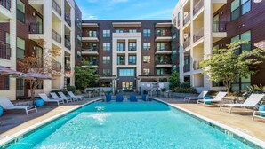 A swimming pool with lounge chairs and a building with multiple balconies. - Mid-Century Charm | Midtown (Nashville)