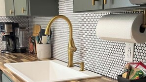 A kitchen with a wooden countertop, a gold faucet, and a built-in stove.