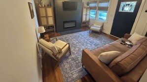 A living room with a fireplace, a sofa, a chair, and a television.