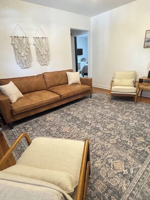 A living room with a brown sofa, a beige armchair, and a patterned rug.