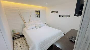 A modern bedroom with a bed, bedside tables, a small plant, and a wall-mounted TV.