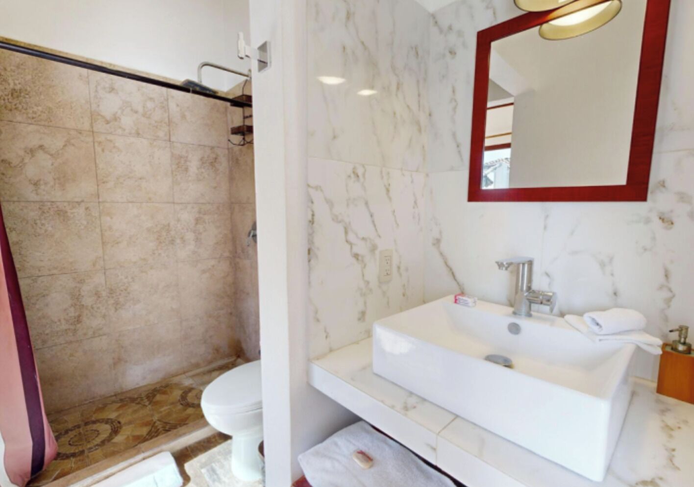 A bathroom with a white sink, mirror, and shower area.