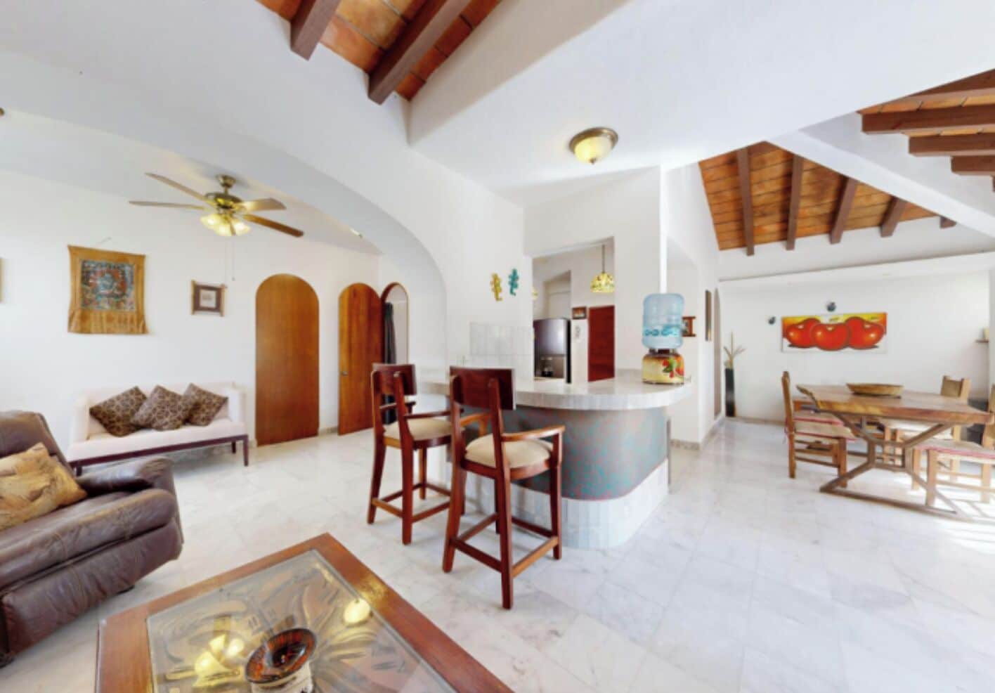 A spacious living area with a sofa, a coffee table, and a dining area with chairs and a table.