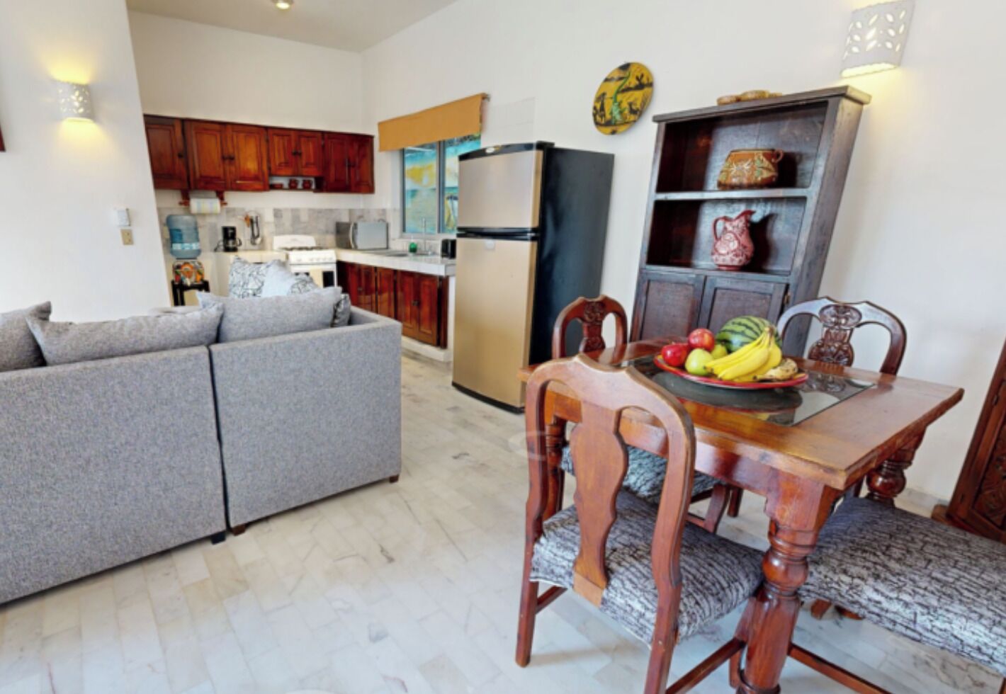 Un espacio habitable compacto con kitchenette, comedor con mesa y sillas, y sofá.