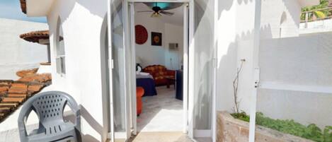 An open doorway leading to a bedroom with a bed, a chair, and a ceiling fan.