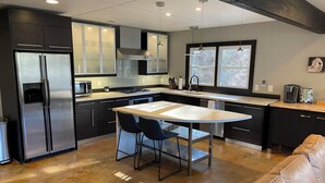 Una cocina moderna con una isla central, electrodomésticos de acero inoxidable y armarios negros.